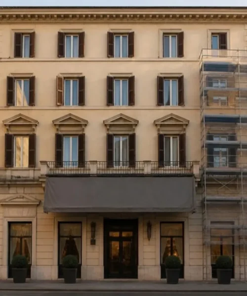 Affiliazione alberghiera: facciata di hotel italiano con insegna in sostituzione e ponteggio leggero